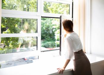 a woman enjoying purified air looks out a window in her Keller home